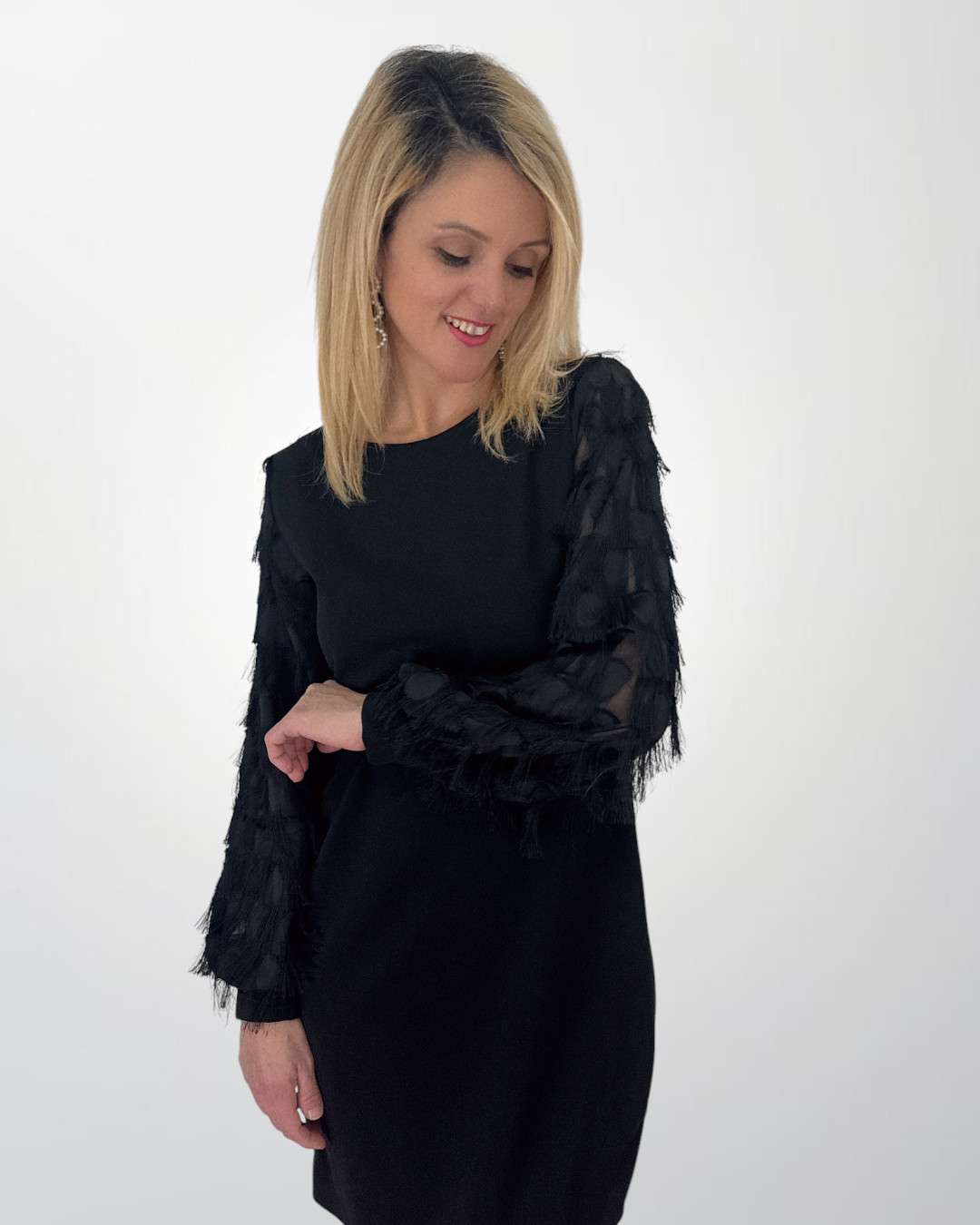 Γυναικεία μαύρο φόρεμα με Διαφάνεια & Κρόσσια στα μανίκια Σε ίσια γραμμή που φτάνει μέχρι το γόνατο, συνδυάζει διαφάνεια και διακριτικά κρόσσια στα μανίκια, δημιουργώντας μια μοναδική εμφάνιση που ισορροπεί ανάμεσα στη θηλυκότητα και τη μοντέρνα αισθητική.