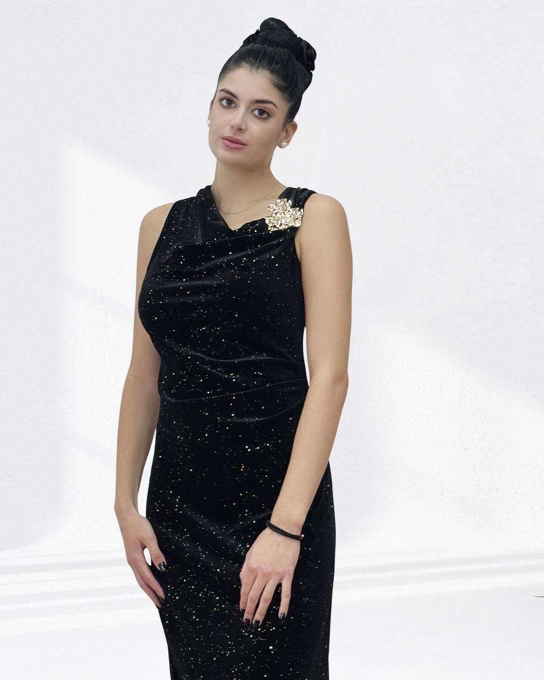 Maxi φόρεμα με βελούδινη υφή strass Μαύρο Maxi γραμμή, με ντραπέ που κολακεύει φυσικά τη σιλουέτα. Χρυσό κόσμημα στον έναν ώμο, διακριτικά στρας που δίνουν glam λάμψη χωρίς υπερβολή. Βελούδινη αίσθηση που προσθέτει ζεστασιά και πολυτέλεια στο look.