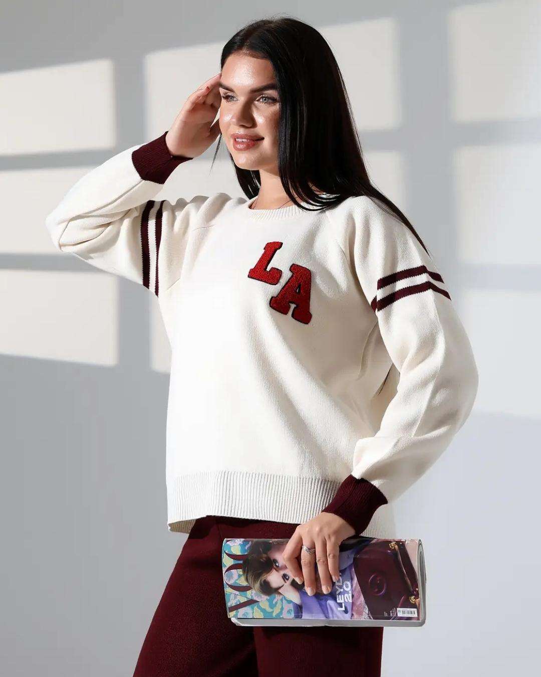 Πλεκτό σετ με με κέντημα LA Εκρού/Μπορντό Πλεκτό σετ δύο τεμαχίων με cozy πουλόβερ και άνετη παντελόνα. Η μπλούζα σε εκρού χρώμα διαθέτει statement κέντημα LA και διχρωμίες που δίνουν μοντέρνο, sporty χαρακτήρα. Καλύπτει στήθος μέχρι 120-125 εκ και έχει μήκος 60εκ. από τον ώμο. Μονόχρωμο Μπορντό παντελόνι σε άνετη γραμμή για εύκολους συνδυασμούς Καλύπτει μέση ως 115-120 εκ και περιφέρεια ως 115-120 εκ Μήκος 106 εκ