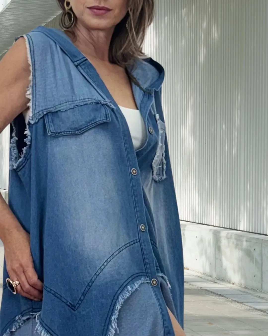 Μακρύ denim Φόρεμα/γιλέκο με oversized γραμμή και σύγχρονο χαρακτήρα. Κλείνει με κουμπιά μπροστά , έχει πλαϊνές τσέπες για πρακτικότητα και ξεφτίσματα που προσθέτουν edgy λεπτομέρεια και κουκούλα. Fit: Oversized γραμμή με χαλαρή εφαρμογή Ύφασμα: 70% Cotton 30% Poliester. Δροσερό μαλακό denim ύφασμα