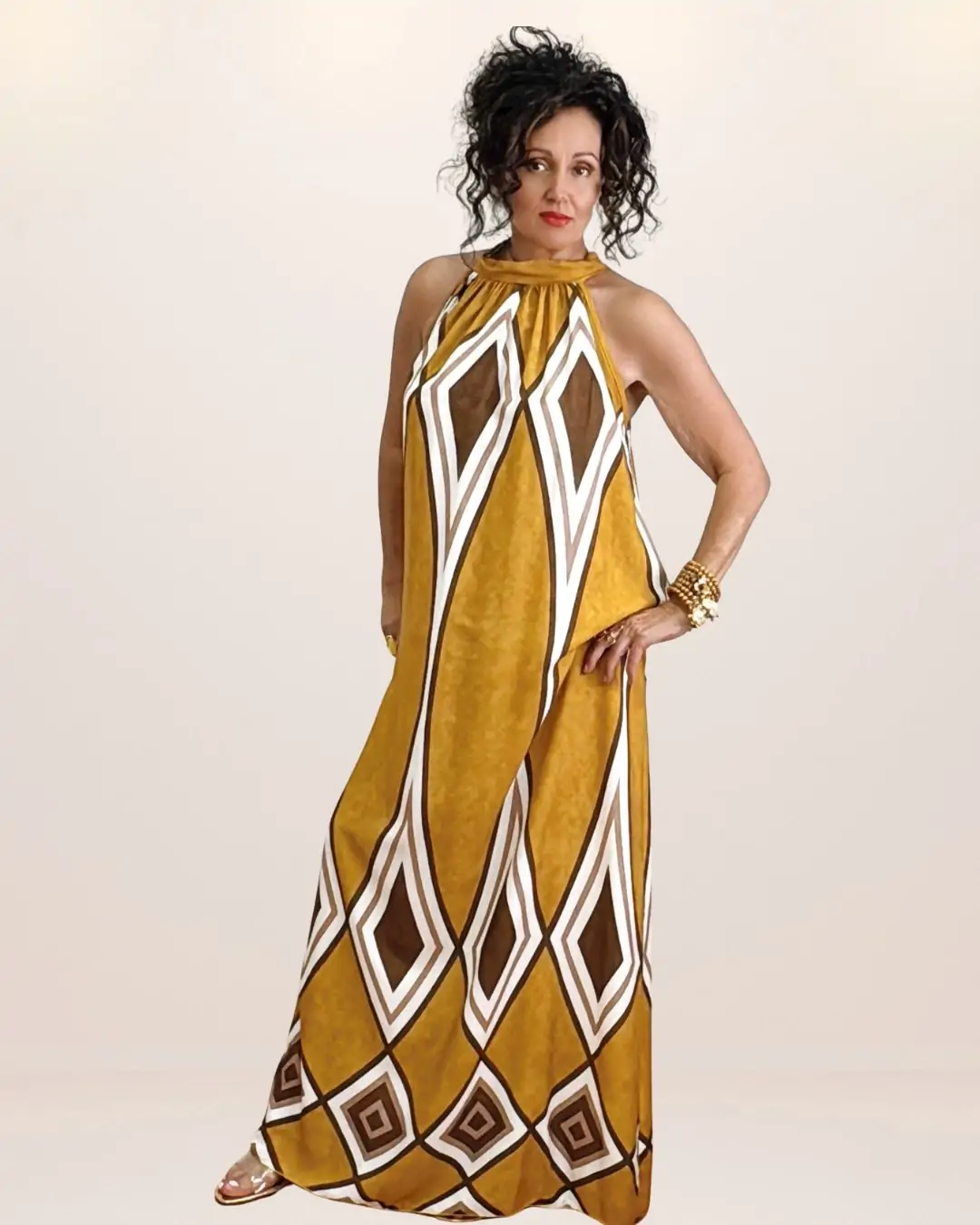 maxi γυναικείο καλοκαιρινό φόρεμα σε δροσερή viscose. Ανοιχτοί ώμου, δένει πίσω με κορδόνι στο λαιμό και έχει γεωμετρικά σχέδια τύπωμα που του δίνει boho και retro chic χαρακτήρα Το βασικό χρώμα είναι ώχρας.